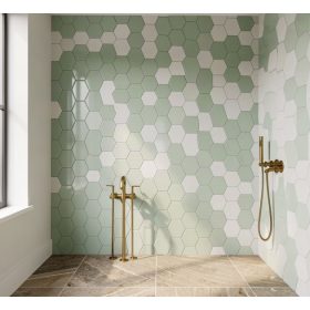 Baño moderno con azulejos hexagonales en verde salvia y blanco, patrón geométrico panal de abeja, grifería dorada